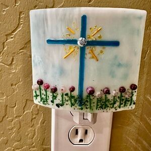 Handmade Glass Nightlight displaying a blue cross in a garden of purple flowers.